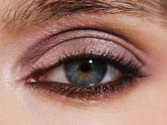 Close-up macro shot of a blue human eye with shimmer eyeshadow and defined eyelashes for Mojeh Magazine.