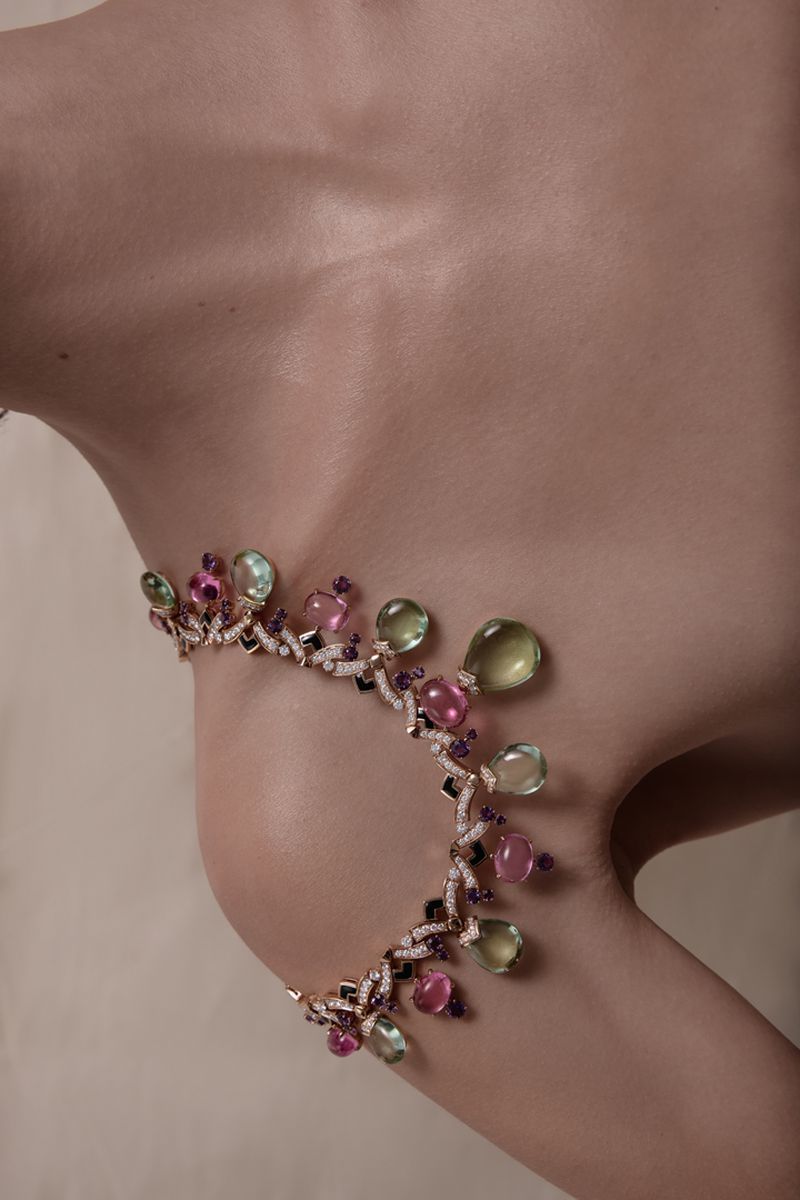Close-up of a model wearing an elaborate gemstone necklace resting on the collarbone and shoulder