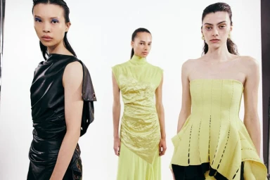 Three female fashion models in contemporary designer clothing posing against a bright white seamless studio background.