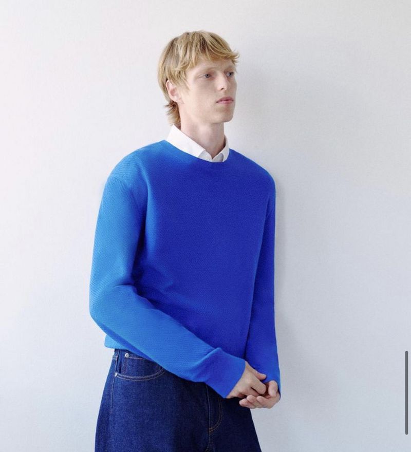 Model wearing a blue sweater and white collared shirt against a white wall for Theory tailored redux