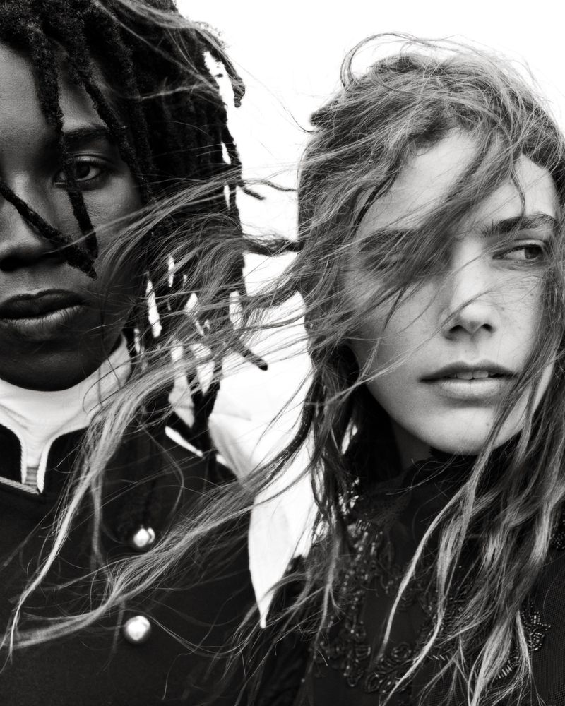 Close-up black and white portrait of two models with tousled hair against a plain bright background