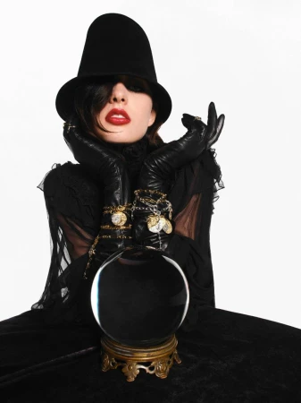 Model in black hat and gloves leaning over a crystal ball for V Magazine editorial Signs From Above