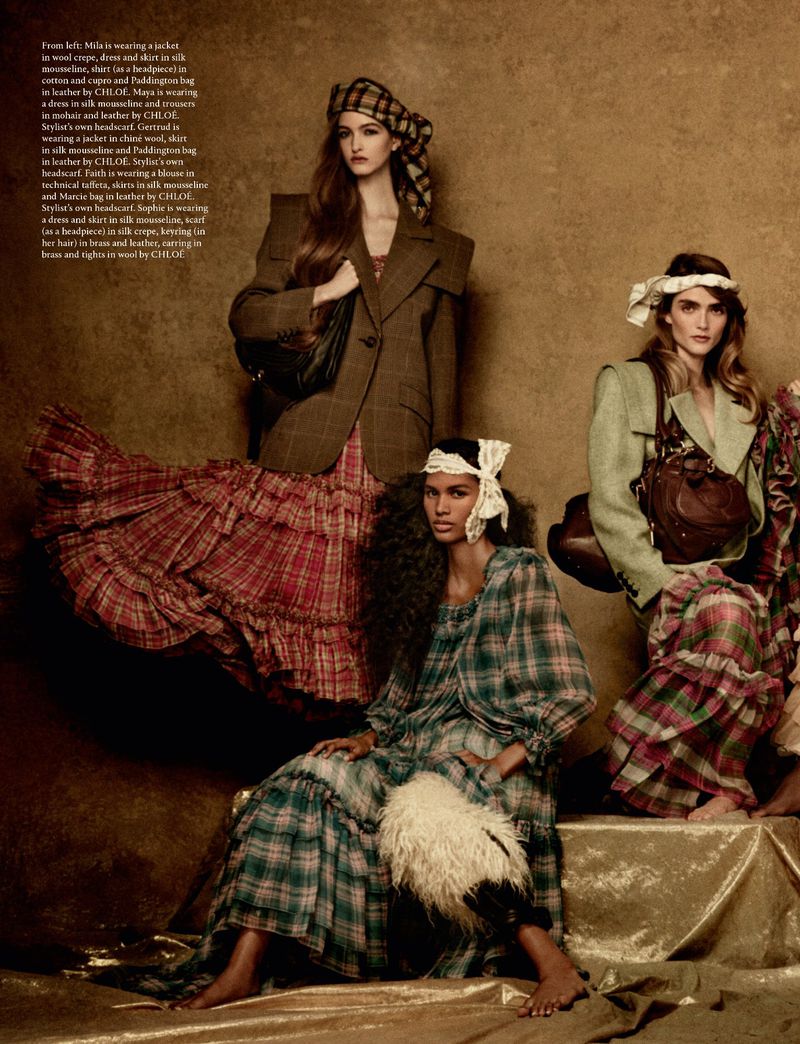 Group of female models in plaid dresses and tailored jackets posing against a textured golden studio background for AnOther Magazine
