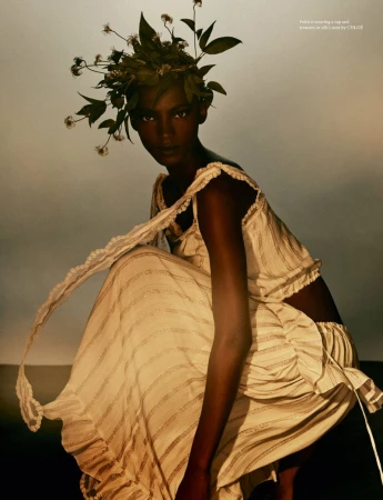 Model wearing white ruffled top and matching skirt with a botanical foliage crown in an editorial photograph for AnOther Magazine.