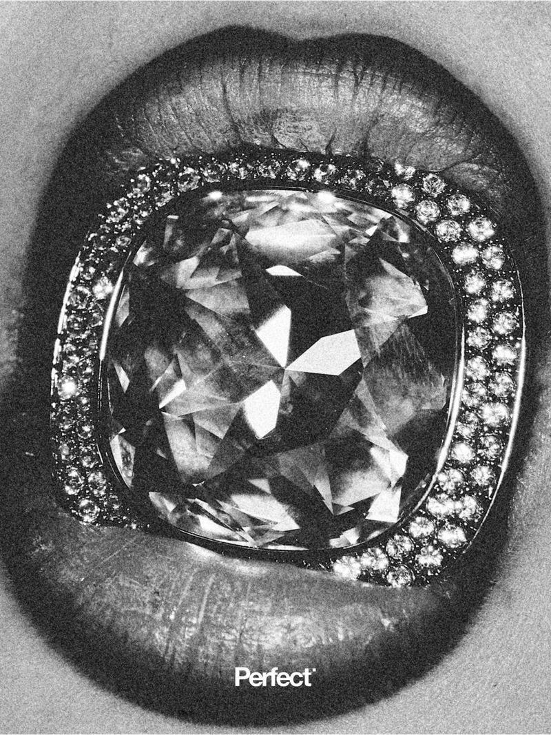 Close-up macro shot of lips holding a large faceted diamond ring in black and white for The Perfect Magazine.