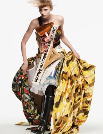 Model wearing sculptural avant-garde dress and tall black boots against a plain white background for AnOther Magazine