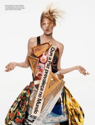 Model wearing sculptural dress constructed from vintage signage, set squares, and curtains against white background.