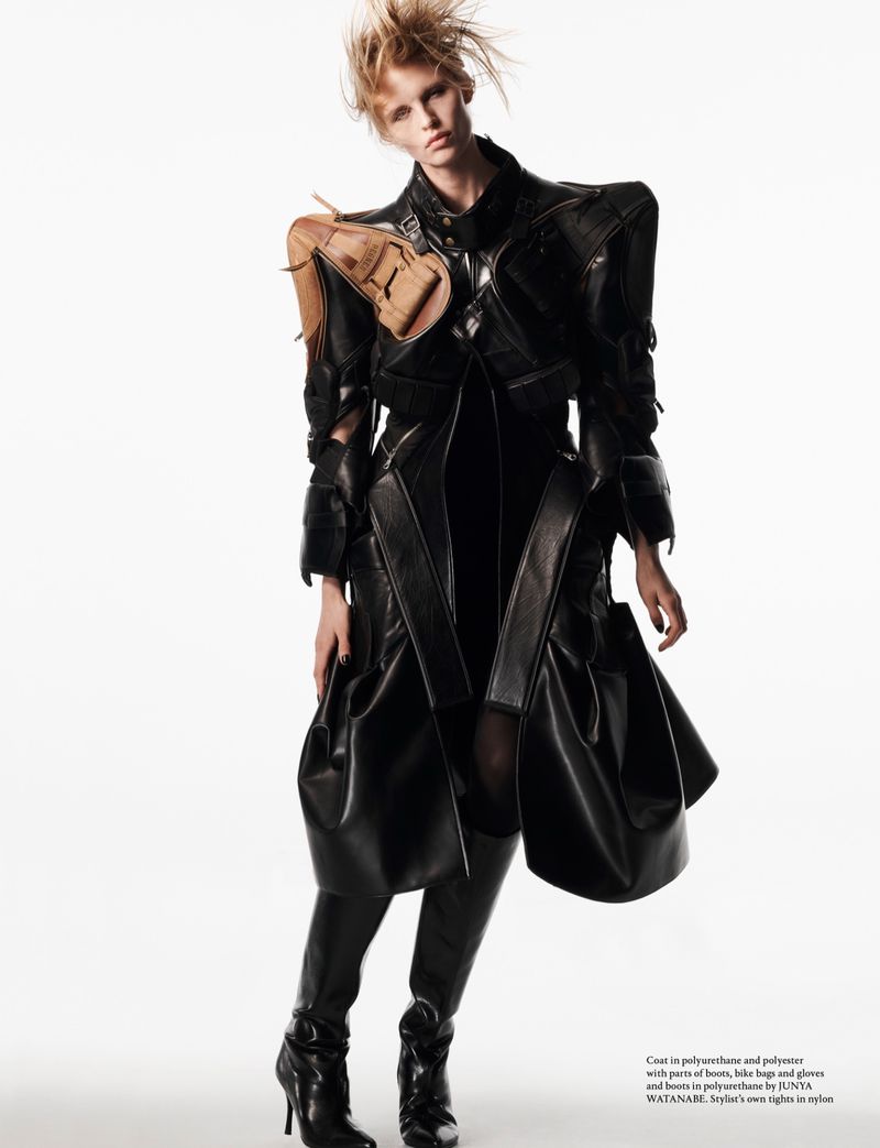 Model wearing avant-garde black leather coat with structured shoulders against white seamless background