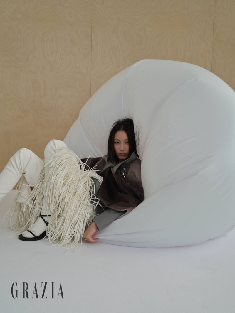 Model seated inside a large white sculptural form against a wooden paneled wall for Grazia Slovenia editorial project