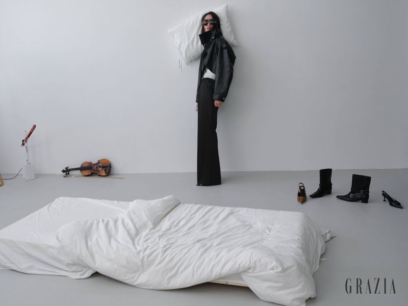 Model standing against a white wall with a pillow behind her head in Grazia Slovenia editorial shoot