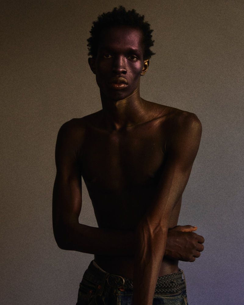 Portrait of a shirtless black man in dark trousers against a neutral background photographed by Riccardo Dubitante