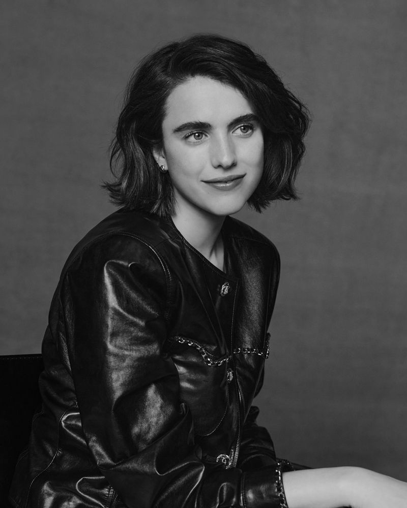 Black-and-white portrait of a young woman with shoulder-length wavy dark hair, wearing a leather jacket and looking to the side.