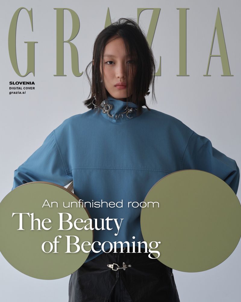 Model wearing a blue high-neck top and dark trousers holding two round green panels against a white background
