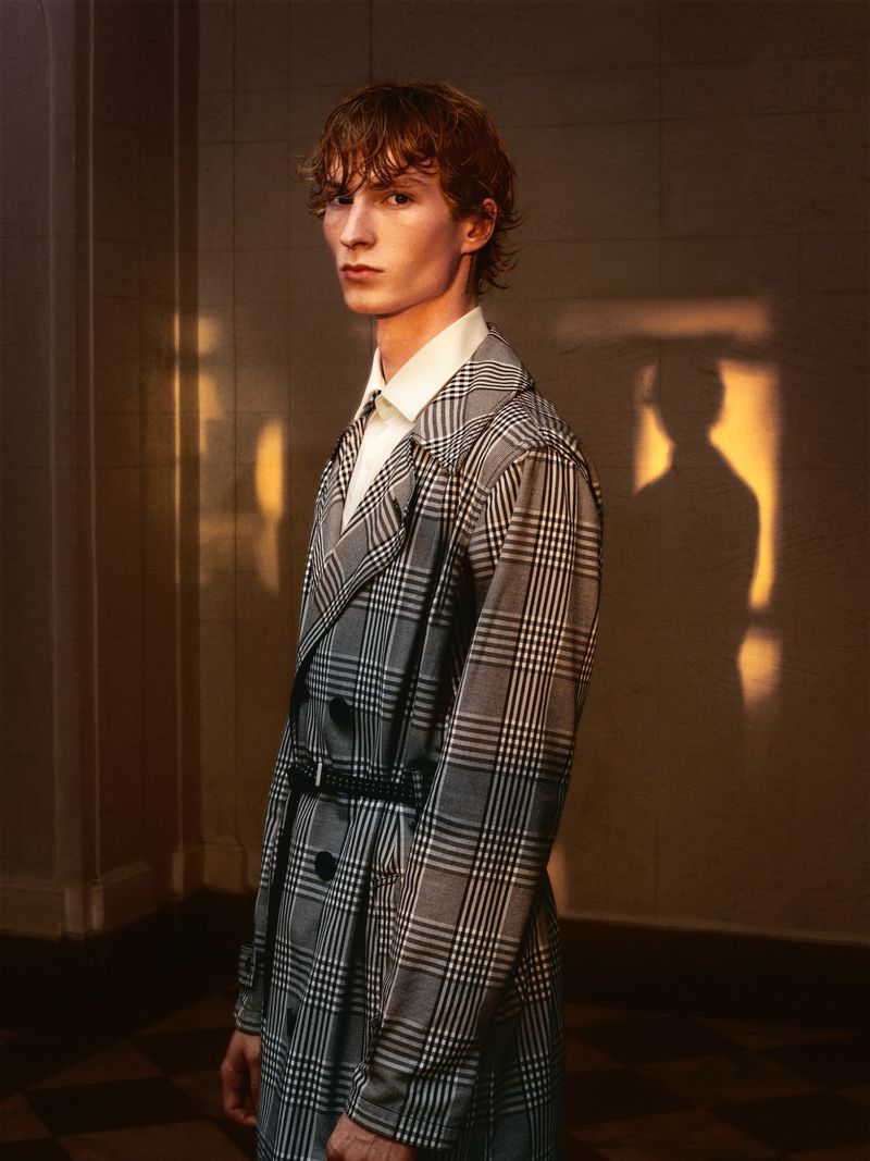 Model Ethan Harwood wearing a grey plaid trench coat with a black belt, photographed by B Charles Johnson.