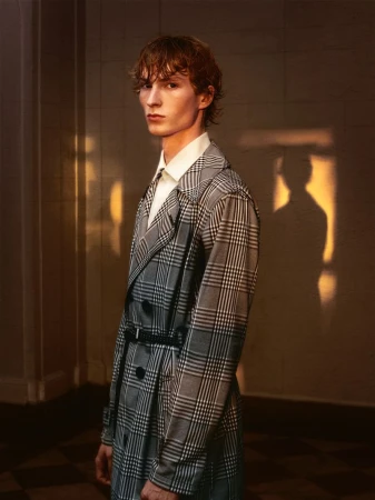 Model Ethan Harwood wearing a grey plaid trench coat with a black belt, photographed by B Charles Johnson.