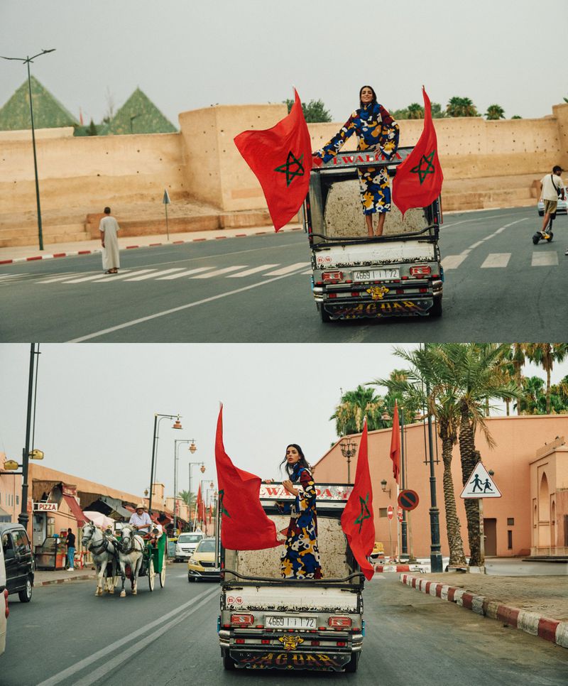Model Nora Attal standing on a truck holding Moroccan flags in street editorial for T: The New York Times Style Magazine MENA