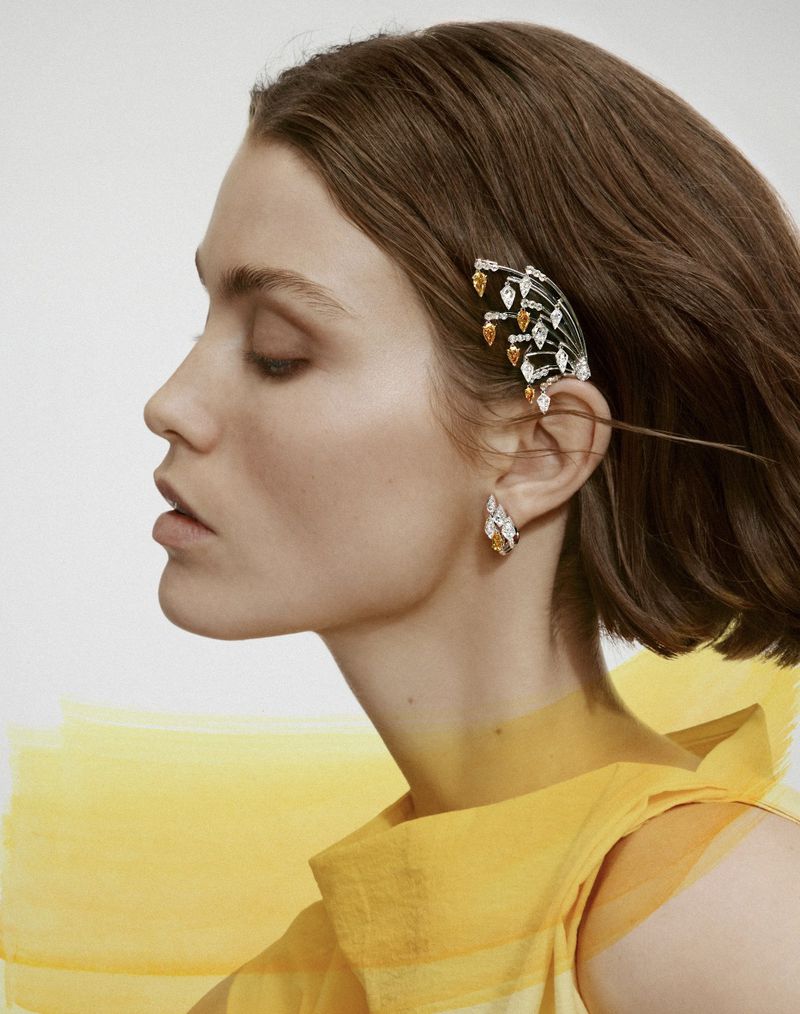 Profile portrait of a woman wearing an elaborate diamond and gemstone ear cuff and matching earring for Cartier Haute Joaillerie.