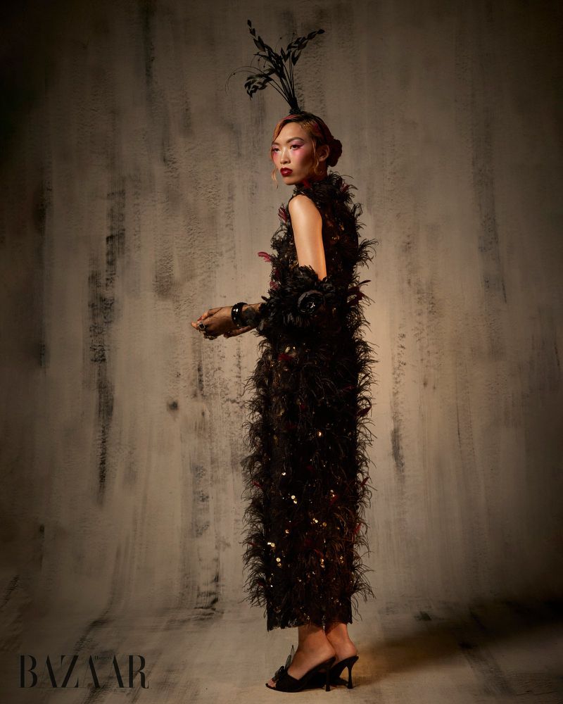 Model Lauren Nguyen wearing a feather-embellished black gown and feathered headdress for Harper's Bazaar Vietnam editorial.