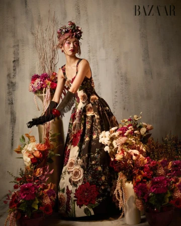 Model Lauren Nguyen in a floral gown posing among arrangements of flowers for Harper's Bazaar Vietnam