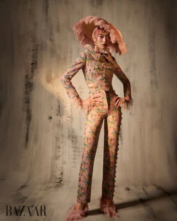 Model Lauren Nguyen wearing floral-print trousers and jacket with a large feathered hat for Harper's Bazaar Vietnam editorial.