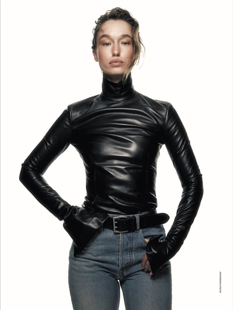 Model in black leather turtleneck and blue jeans against a white background for Elle Italia