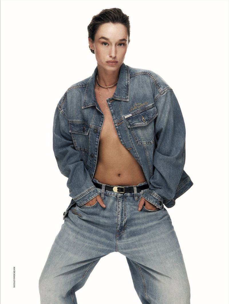 Model wearing an oversized denim jacket and jeans against a plain white background for an editorial spread.