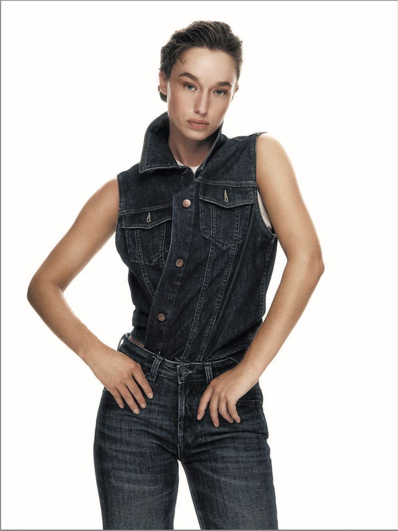Model wearing dark denim vest and matching jeans posing against a white background for Elle Italia