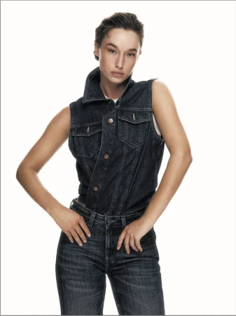 Model wearing dark denim vest and matching jeans posing against a white background for Elle Italia
