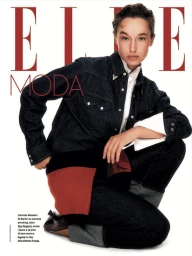 Model crouching wearing a dark denim western shirt and matching jeans against a bright white background for Elle Italia
