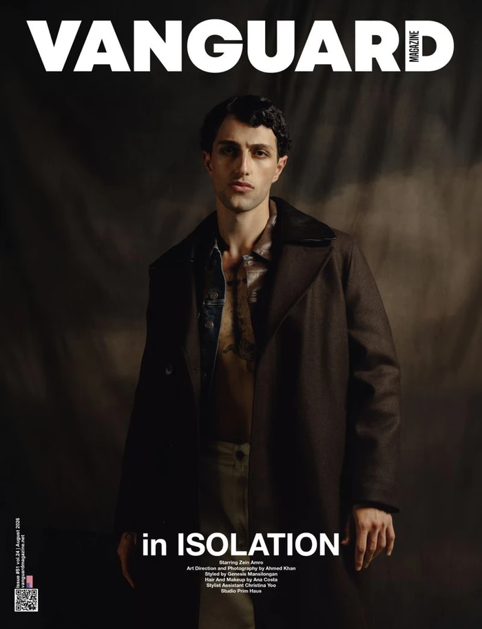 Man wearing a dark brown coat over an open shirt against a textured backdrop for Vanguard Magazine