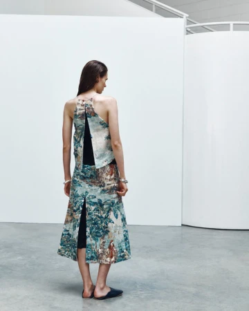 Model seen from behind wearing a patterned halter top and matching skirt in a modern white studio interior.