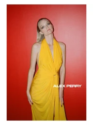 Model Gemma Ward wearing a bright yellow halterneck dress against a vivid red background for Alex Perry Pre-Fall 2026 Lookbook.