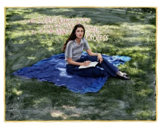Woman sitting on a blue blanket on grass holding a notebook, with handwritten text overlaid across the upper background.
