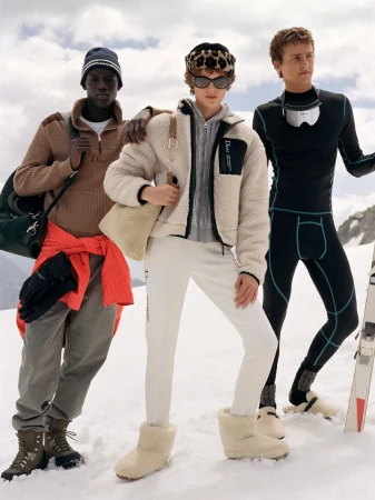 Three models wearing winter alpine apparel and boots standing on a snowy mountain slope for Dior Alps campaign.