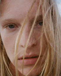 Close-up portrait of blonde model Angelina Kendall with stray hair across her face, photographed by Drew Vickers for H&M.