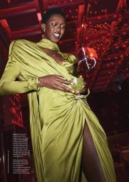 Model Adama Jobe in a draped chartreuse silk dress holding a cocktail glass under red lighting with a disco ball