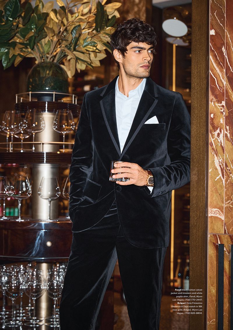 Man wearing a black velvet suit holding a glass in a bar interior for Night Shift by Modern Luxury