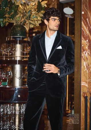 Man wearing a black velvet suit holding a glass in a bar interior for Night Shift by Modern Luxury