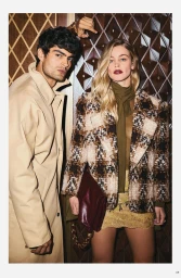 Editorial portrait of a male and female model posing against a dark patterned wall in stylish apparel for Modern Luxury