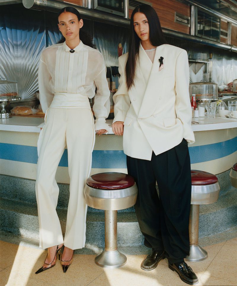 Two models posing inside a retro diner wearing tailored formal wear photographed by Nadine Ijewere for WSJ