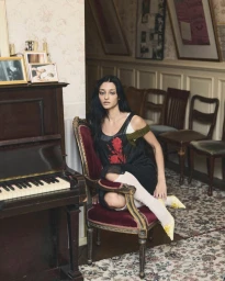 Sofie Royer seated on a vintage armchair next to an upright piano in Numéro Berlin editorial by Emil Dietrich