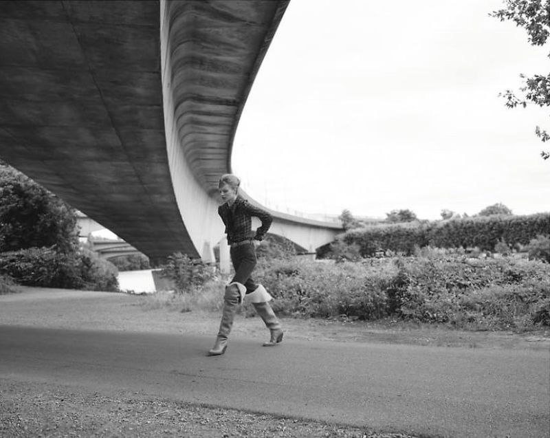 Model walking on a path beneath a large concrete bridge structure for L'Obs Magazine editorial by Giuseppe Triscari.