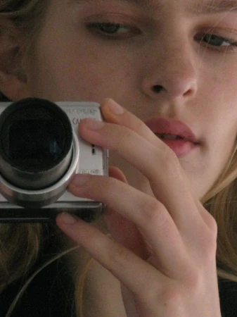 Close-up portrait of model Victoria Volt holding a silver digital camera to her face for DNA Magazine Mexico shot by Geray Mena.