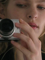 Close-up portrait of model Victoria Volt holding a silver digital camera to her face for DNA Magazine Mexico shot by Geray Mena.