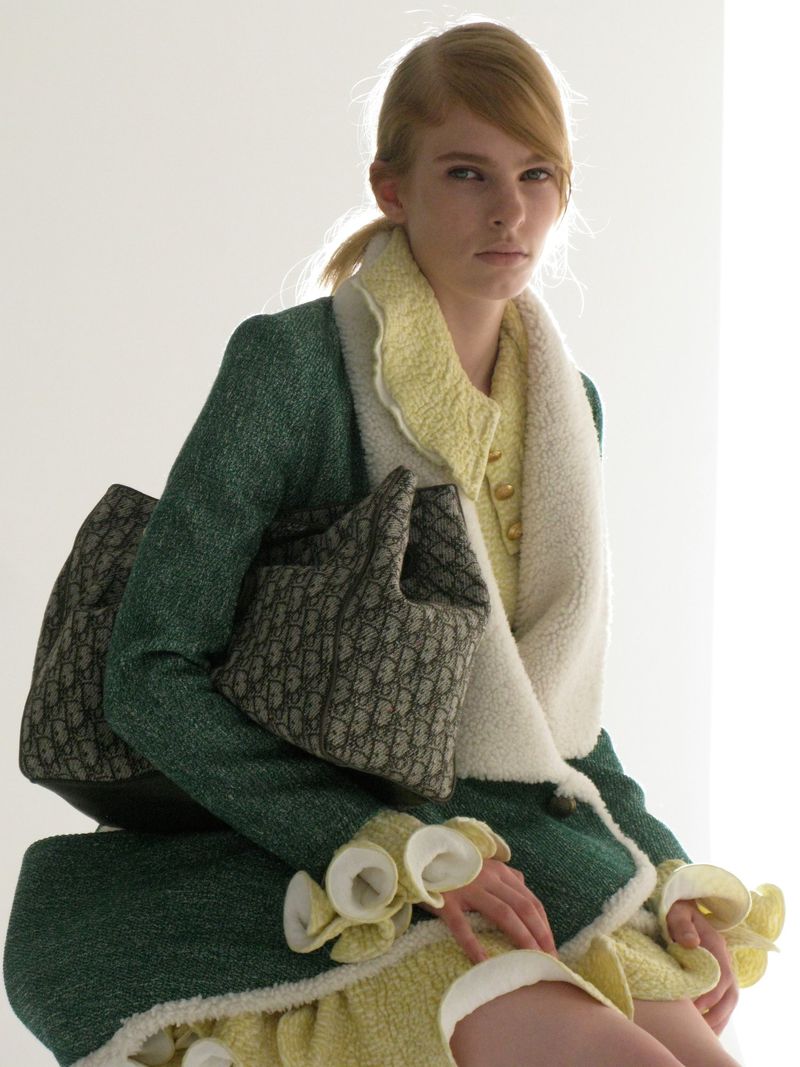 Model Victoria Volt holding a patterned handbag, wearing a green coat and yellow dress for DNA Magazine Mexico, photographed by Geray Mena.