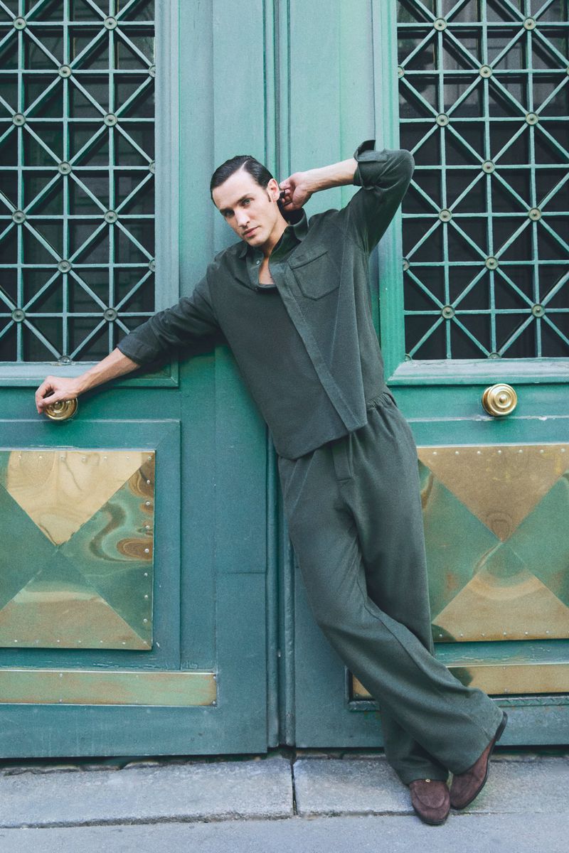 Model Federico Novello leaning against large green double doors in an editorial portrait for Marie Claire Czech Republic.