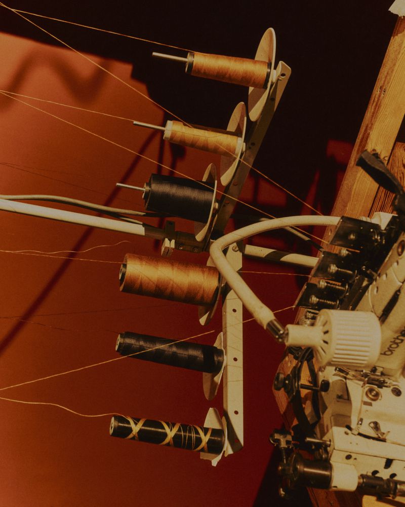 Close-up of a sewing machine thread stand loaded with multiple spools of thread and fine threads extending outward against a dark background