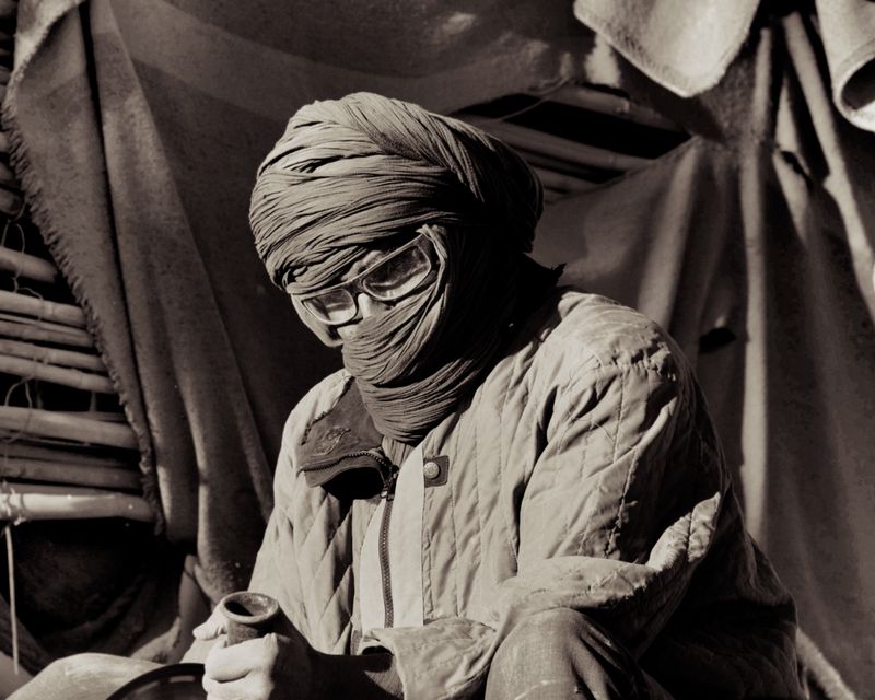 Portrait of a person wrapped in a turban and quilted jacket wearing protective glasses, photographed by Max Miechowski for Atmos Magazine.