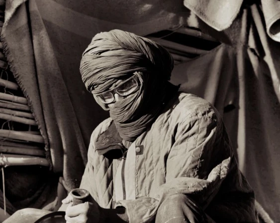 Portrait of a person wrapped in a turban and quilted jacket wearing protective glasses, photographed by Max Miechowski for Atmos Magazine.