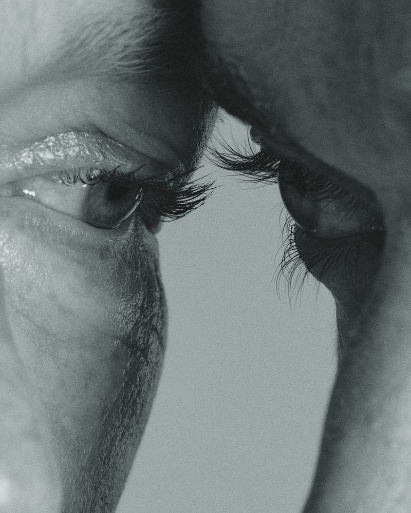 Close-up black and white macro shot of human eyes and eyelashes facing each other.